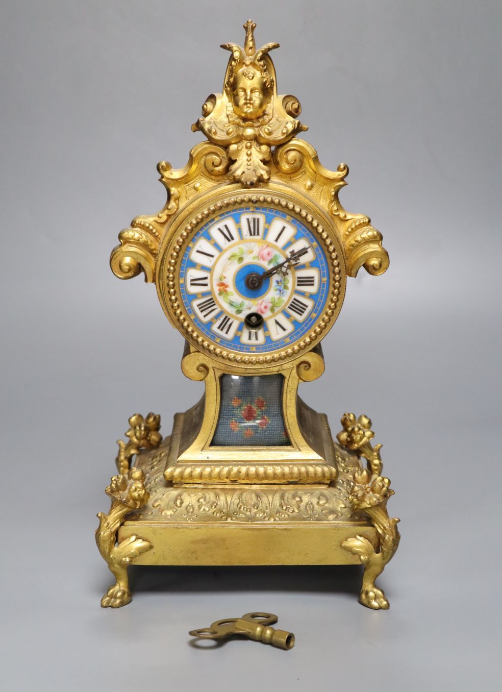 A 19th century French gilt metal mantel timepiece, with ceramic dial, pendulum and key, 31cm